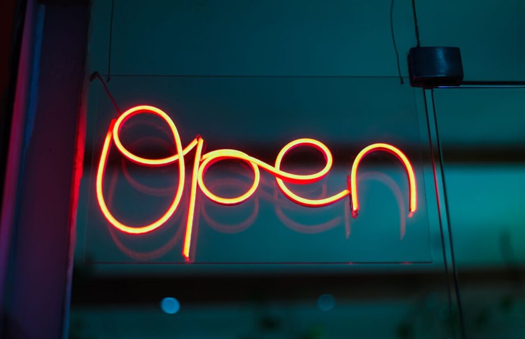 The Art of Drawing Readers In: Your attractive post title goes here Bright red neon 'Open' sign glowing in a shop window at night.